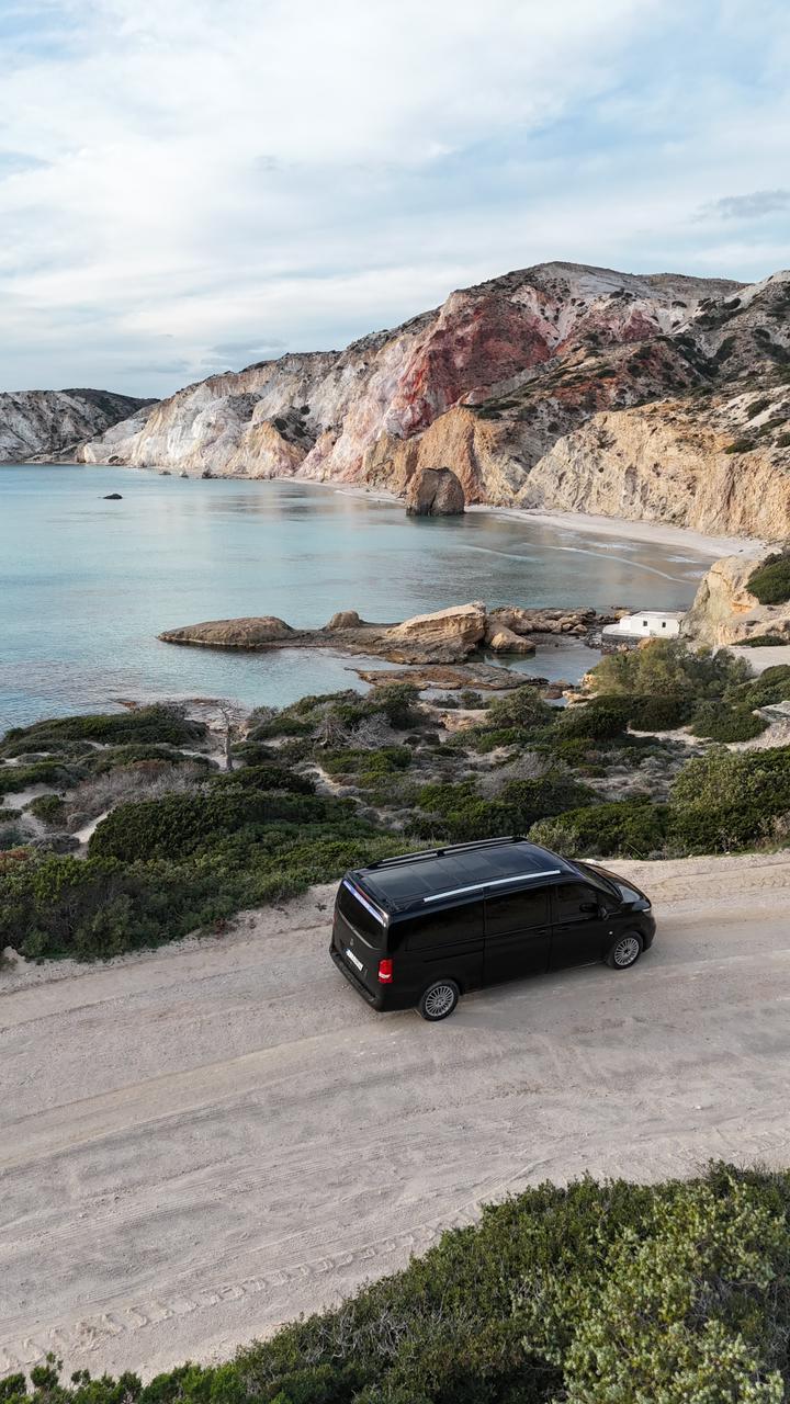 Elysium Transfer Milos vehicle on a coastal road above a bay