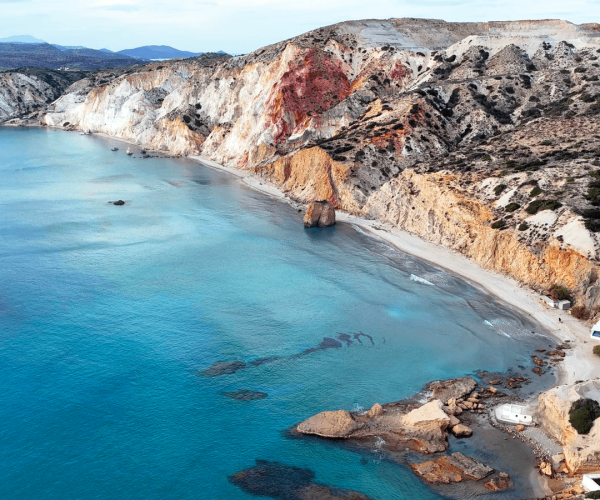 Turquoise shallow water and coloured cliffs at a beach on Milos