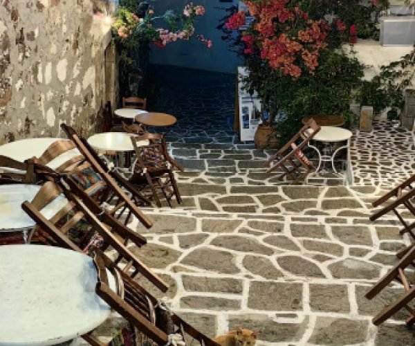 Tables in a narrow whitewashed village lane on Milos in the evening